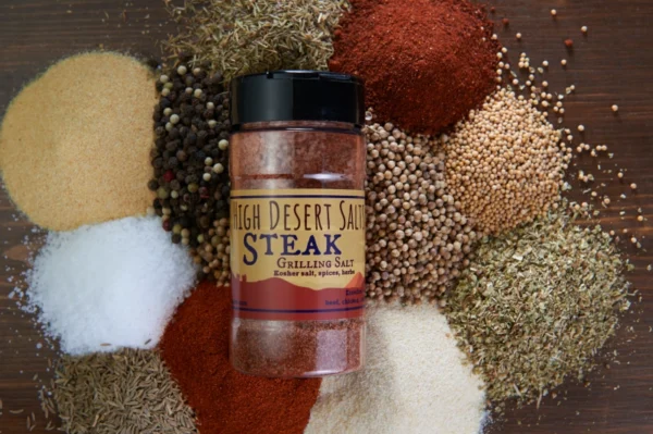 A jar of steak seasoning on top of many different spices.